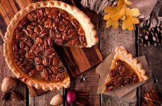 Autumn pecan pie, overhead table scene with cut slice on a rustic wood background